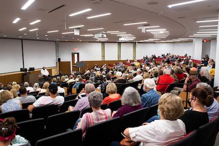 Photograph of a packed auditorium in Merrill Hall. 